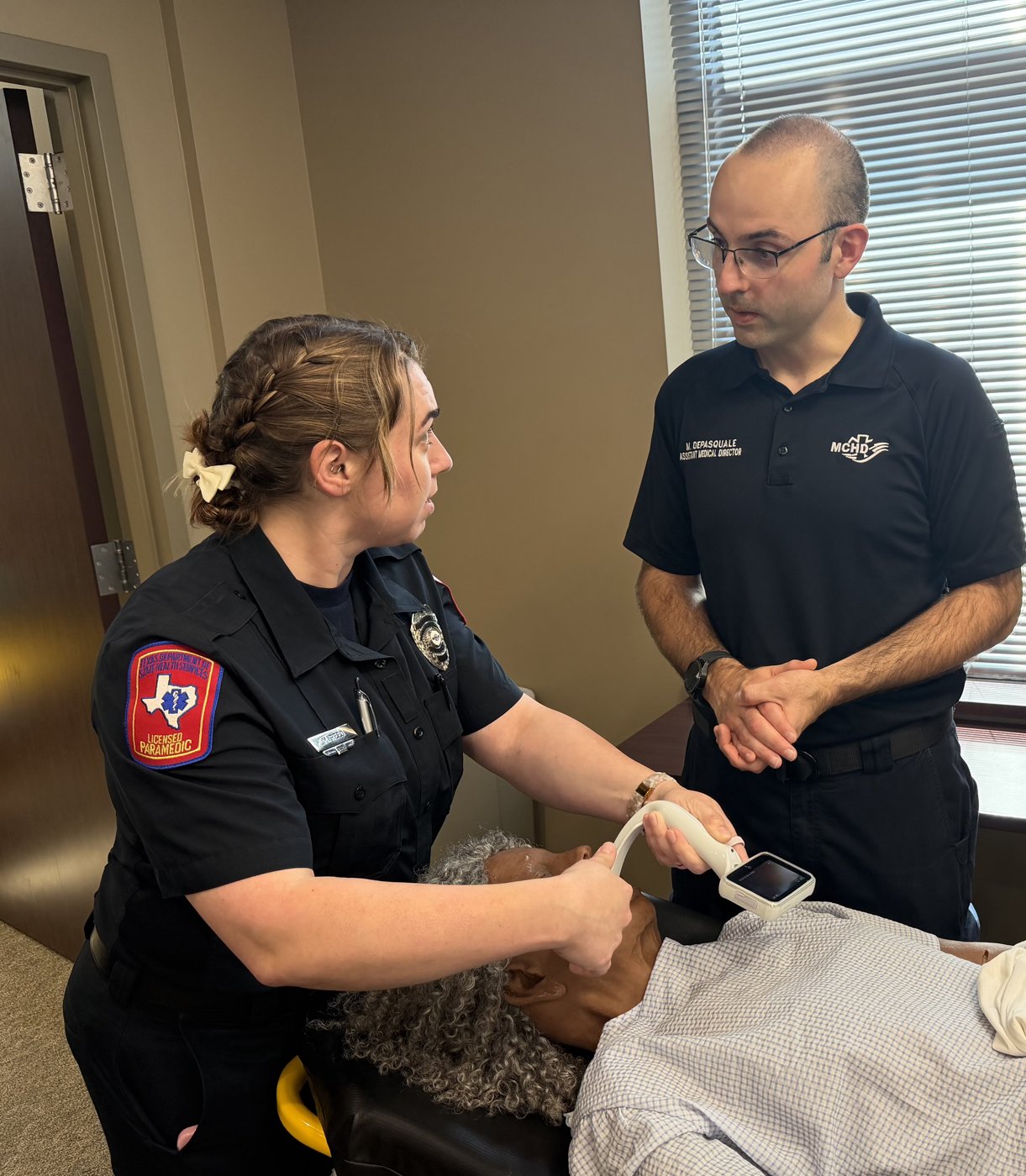 Dr. Michael DePasquale instructing a paramedic performing an ultrasound-guided airway procedure on a manikin.