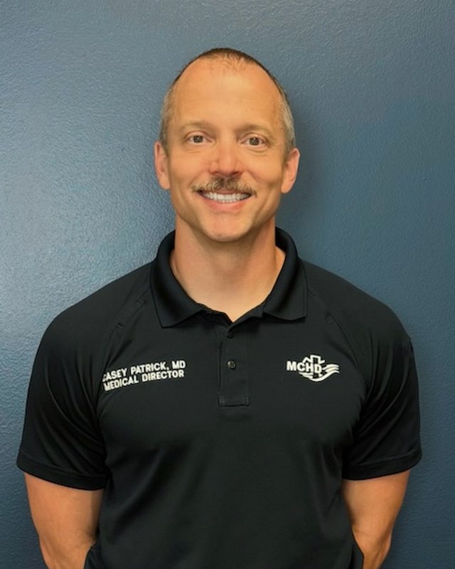 Dr. Casey Patrick in a black MCHD polo shirt embroidered with his name and title.